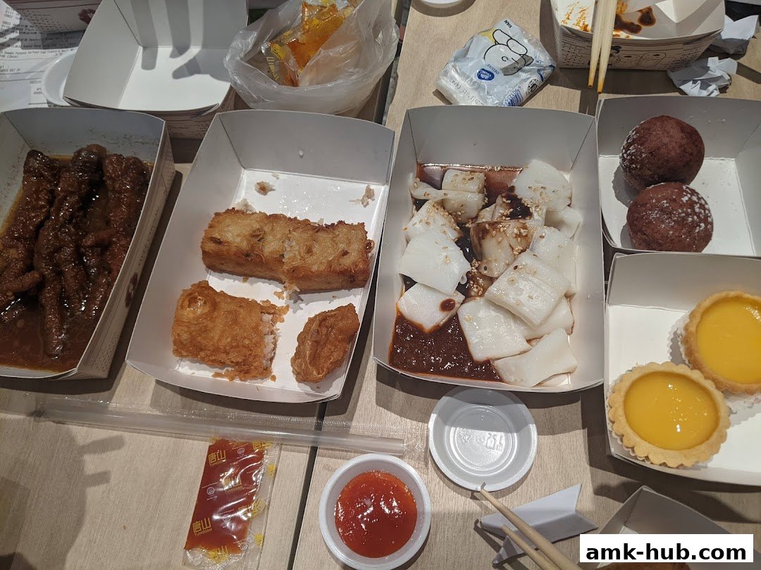 A spread of various dim sum dishes including chicken feet, fried items, rice noodle rolls, and tarts.