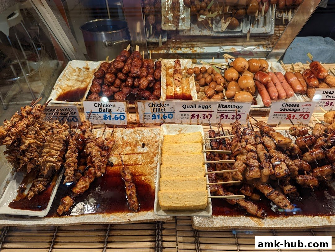 A display of various Japanese skewers and snacks, including chicken, sausages, and eggs.