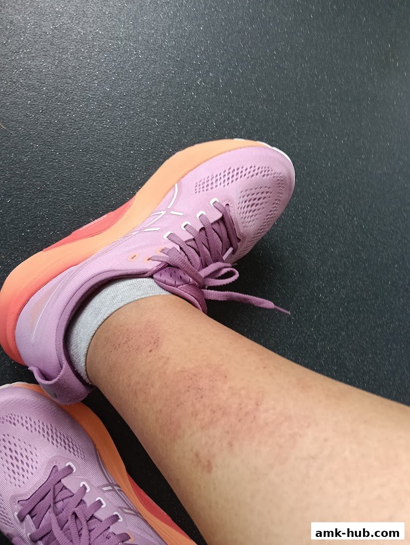 A close-up of a person's leg wearing purple athletic shoes with orange accents.