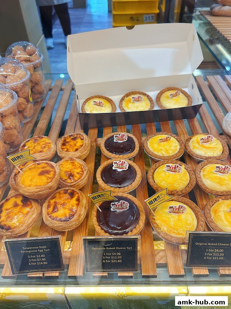 A display of freshly baked tarts, including Portuguese egg tarts and cheese tarts.
