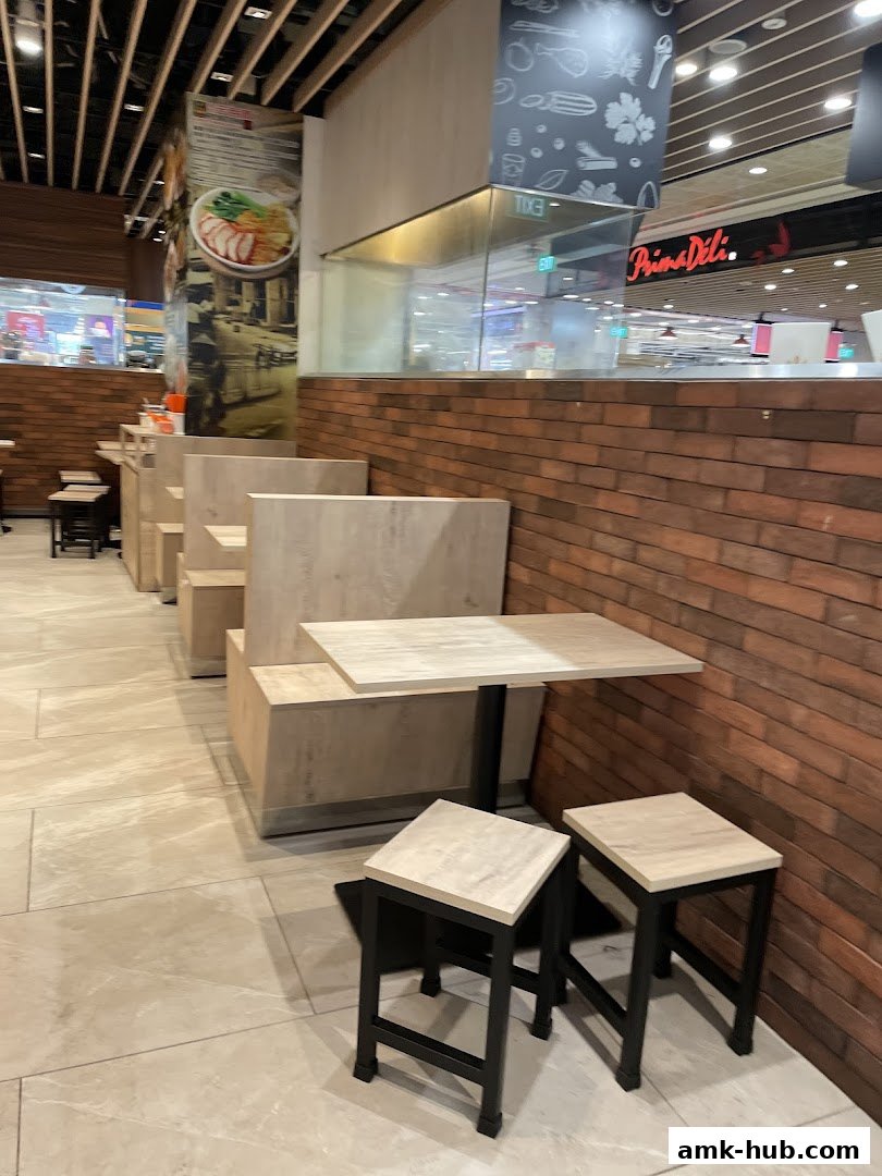 Interior seating area of Pontian Wanton Noodle with tables, stools, and brick wall.