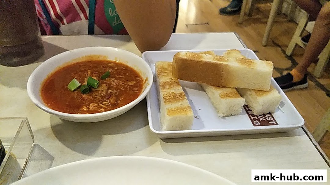 A close-up of toast with a side of savory sauce, garnished with green onions.