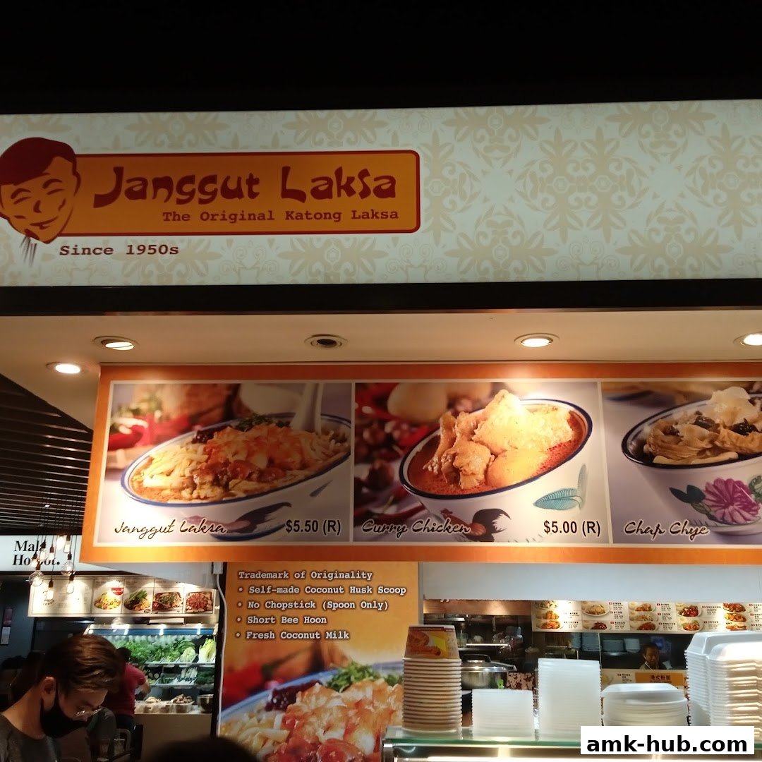 A sign for Janggut Laksa, showcasing popular dishes like Laksa and Curry Chicken.