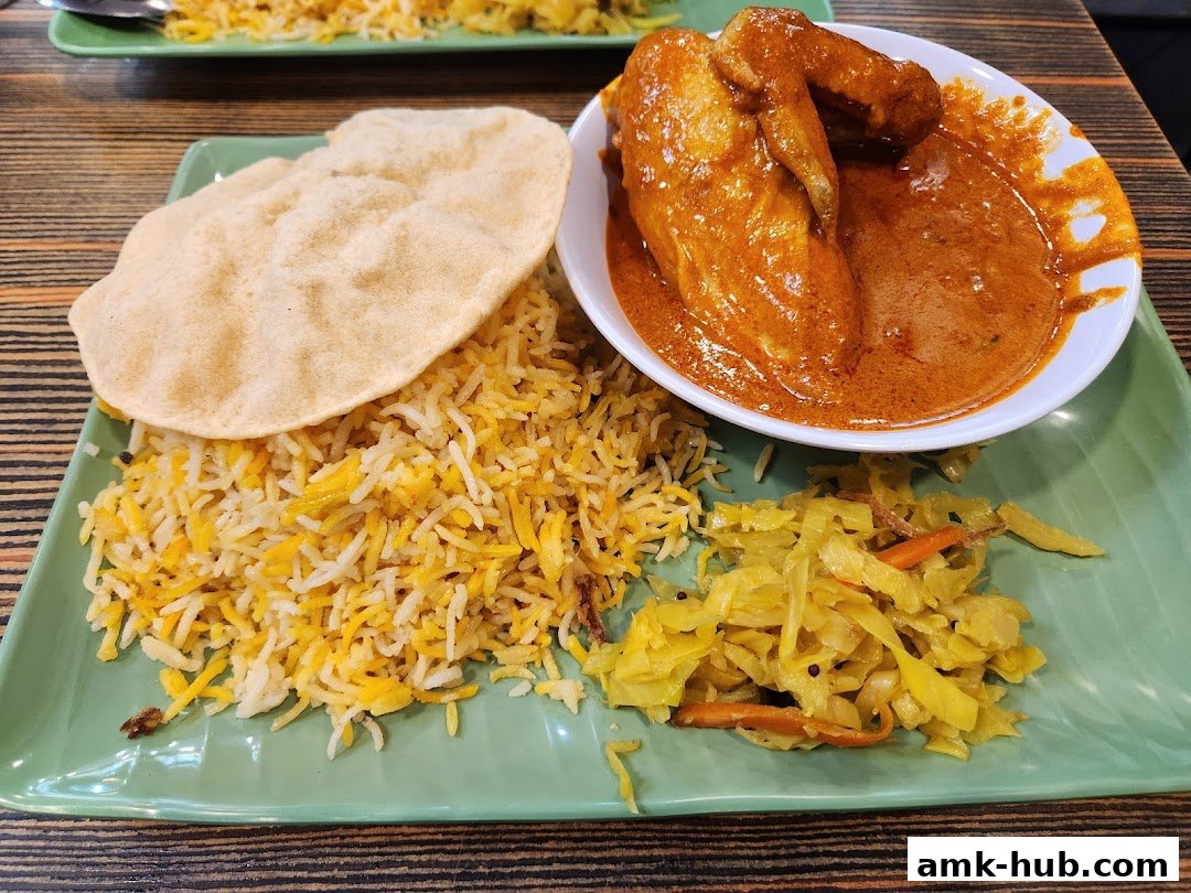 A plate of biryani with chicken curry, papadum, and pickled cabbage.