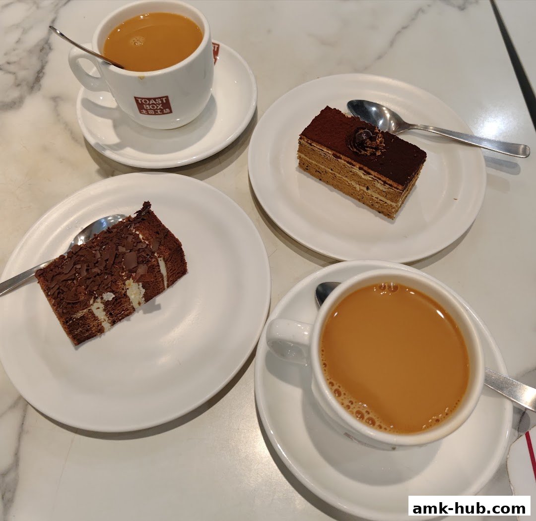 Two slices of cake and two cups of coffee on a marble table.