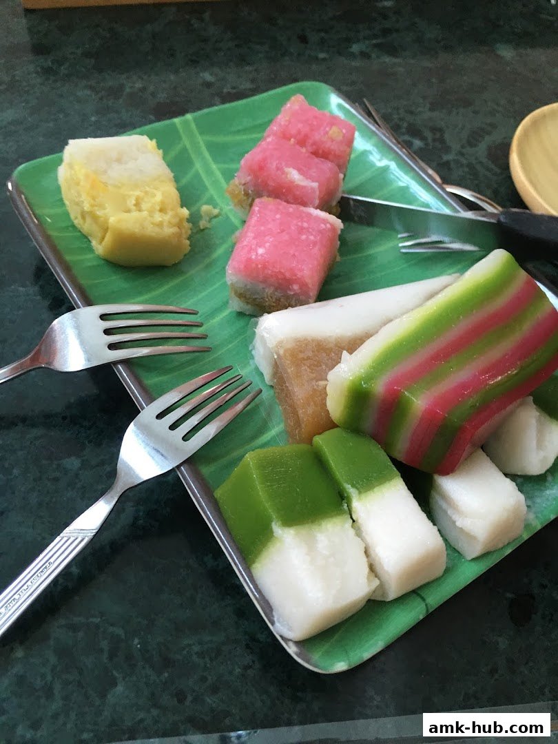 A plate of colorful Indonesian kue or traditional cakes served with forks.