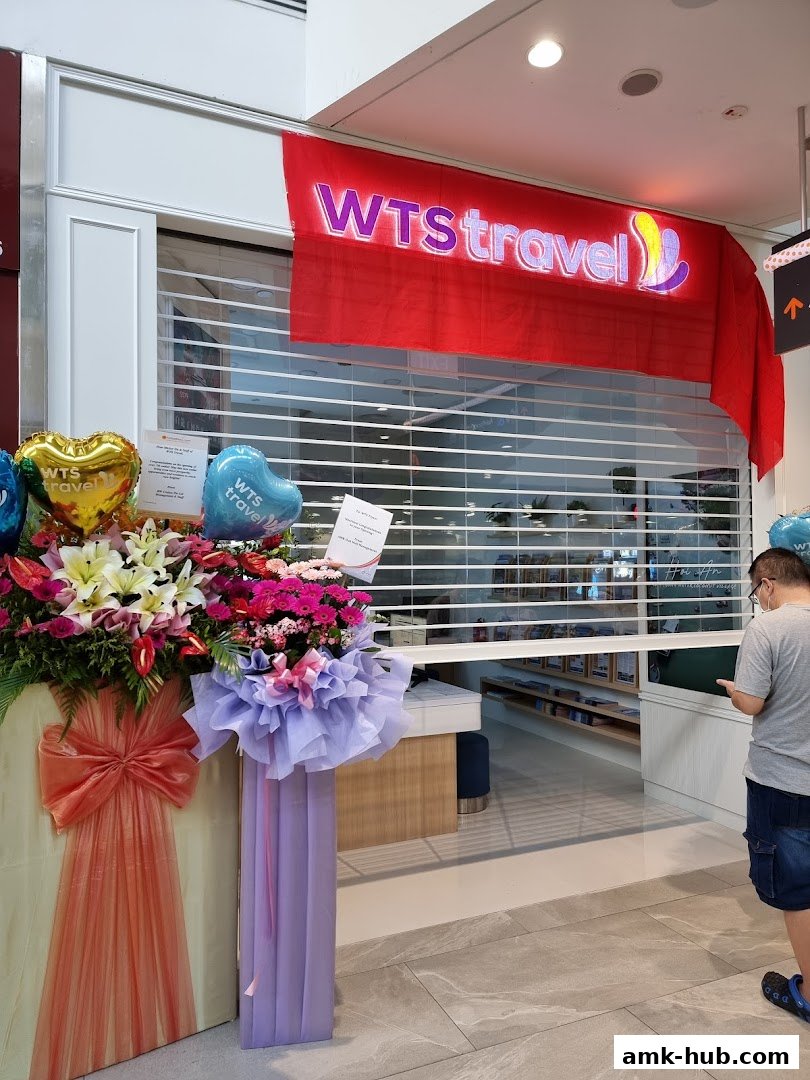 The WTS Travel shop front with a red banner and floral decorations.