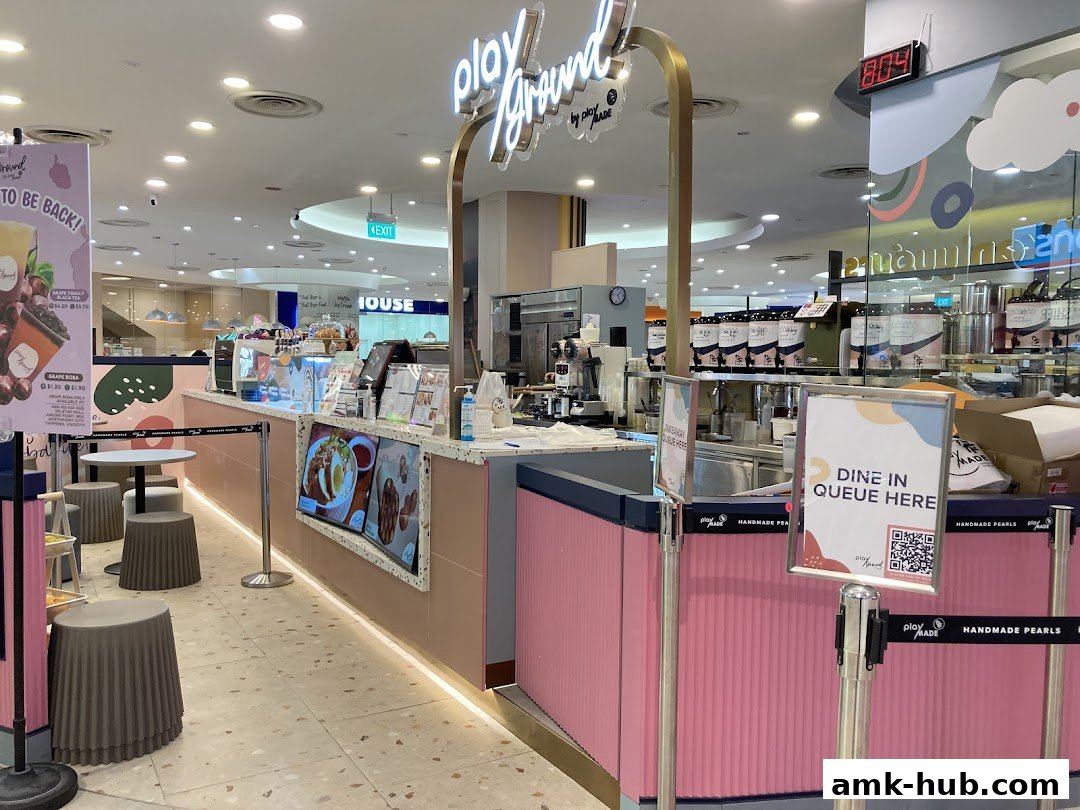 The Playground by PlayMade shop front with a pink counter, seating, and signage.