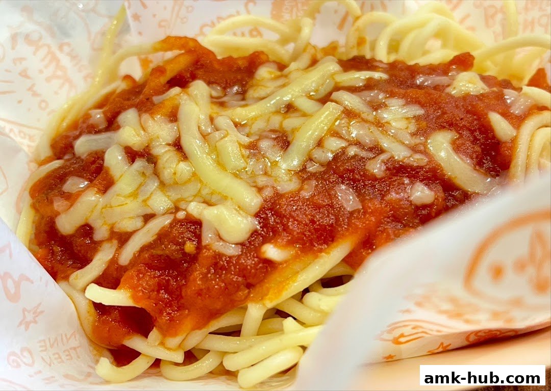 A close-up shot of Popeyes spaghetti with marinara sauce and melted cheese.