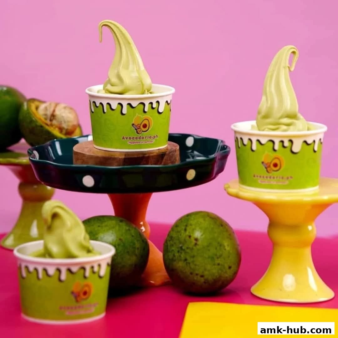Avocadoria soft serve ice cream cups with fresh avocados on a pink background.