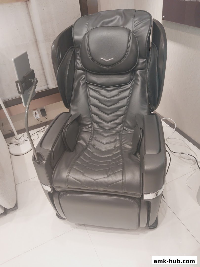 A luxurious black massage chair with an attached tablet holder.