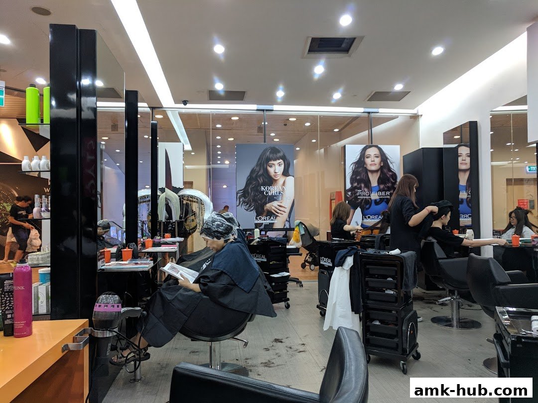 Interior of a busy hair salon with clients receiving treatments and stylists working.