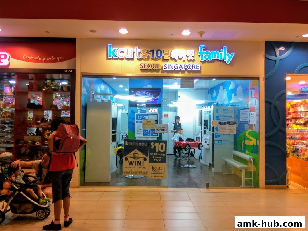 The entrance of a kcuts hair salon with a child getting a haircut in a car-shaped chair.