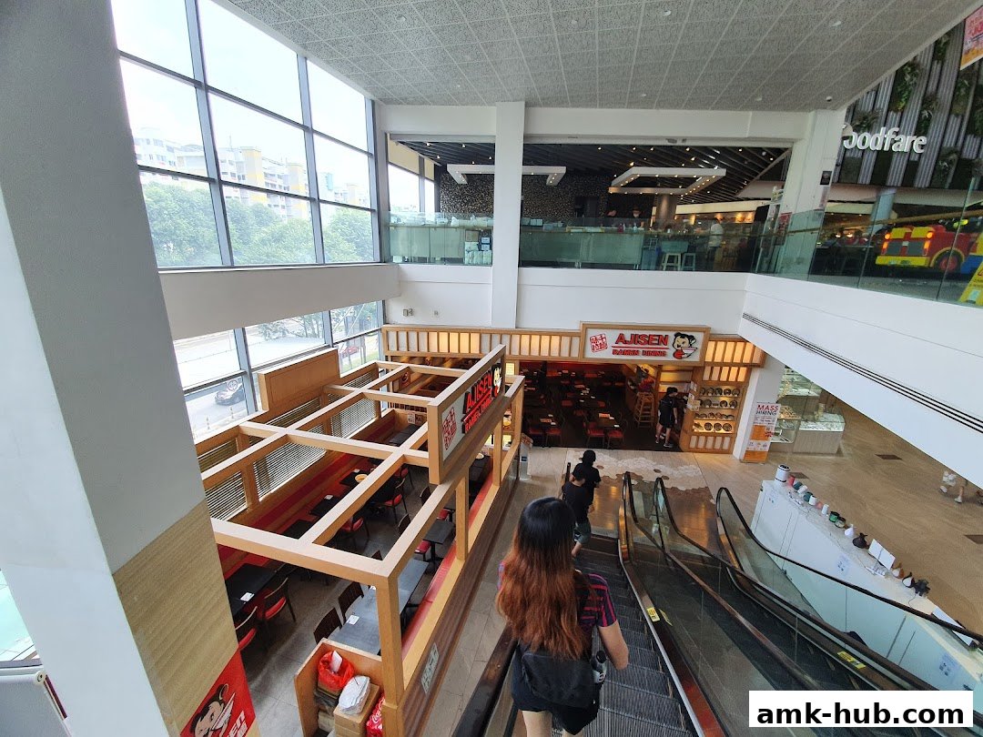 View of a Japanese ramen restaurant and escalators in a shopping mall.