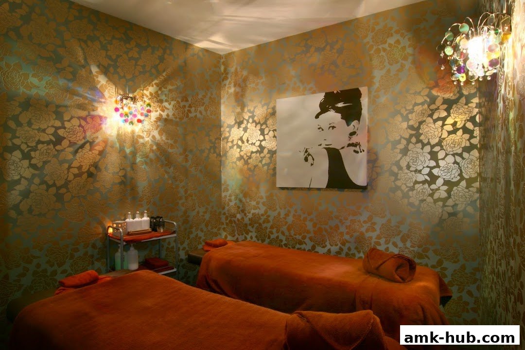 A serene spa room with two massage beds, elegant floral wallpaper, and decorative lighting.