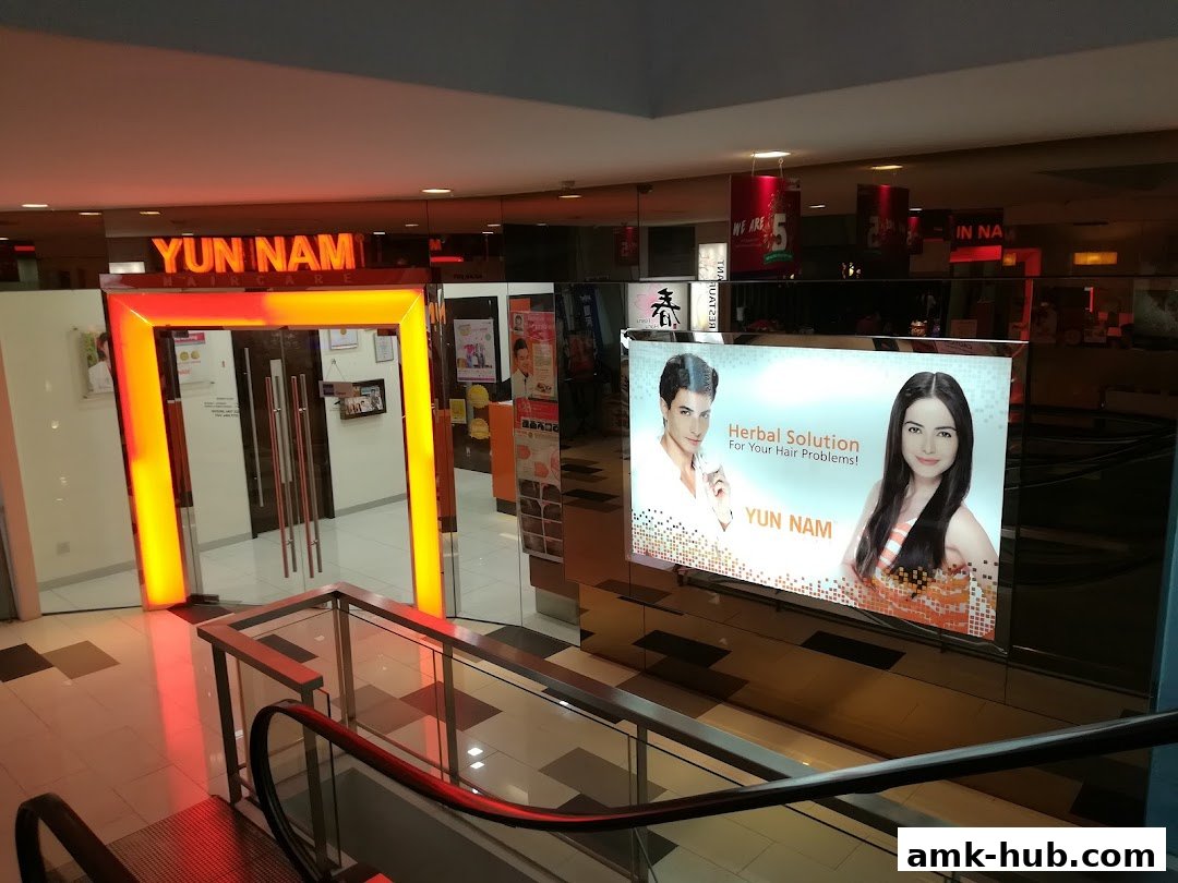 The entrance to Yun Nam Hair Care, featuring a bright orange illuminated doorway and a large advertisement.