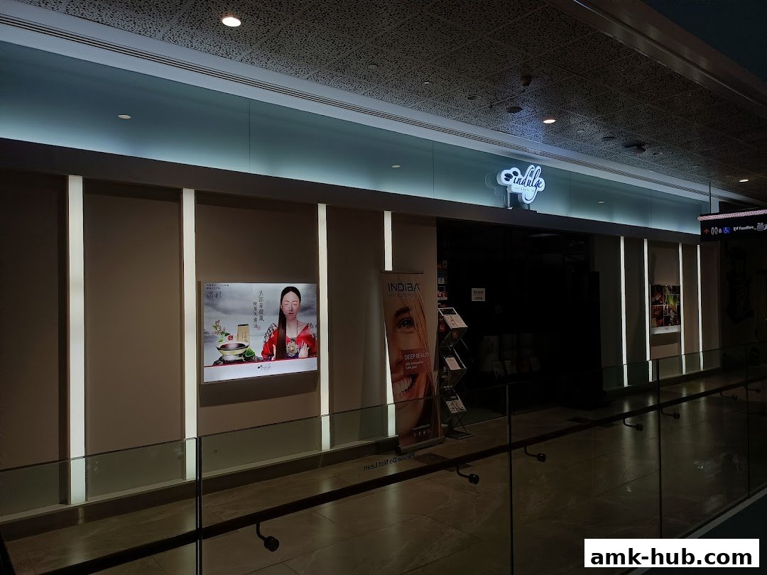 The modern storefront of Indulge Skin & Body Lab with illuminated signage and promotional displays.