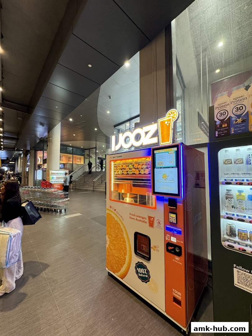 A bright orange juice vending machine with a large orange graphic and the brand name 'iJooz'.