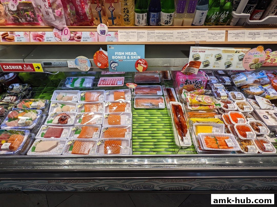 A display of fresh seafood and Japanese food items, including sushi and sashimi, in a market.