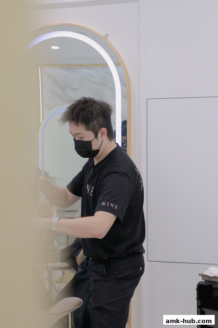 A hairstylist wearing a mask works on a client's hair in a modern salon.