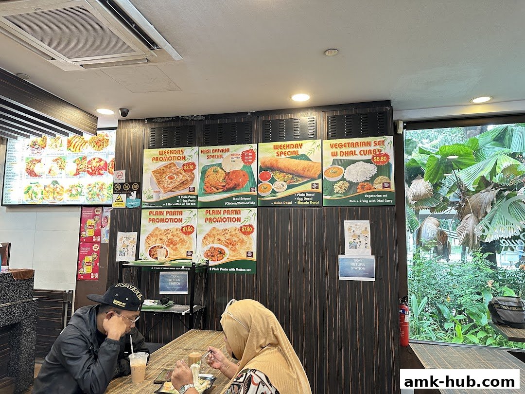 Diners at Prata Raya restaurant, with promotional posters and a menu board visible.