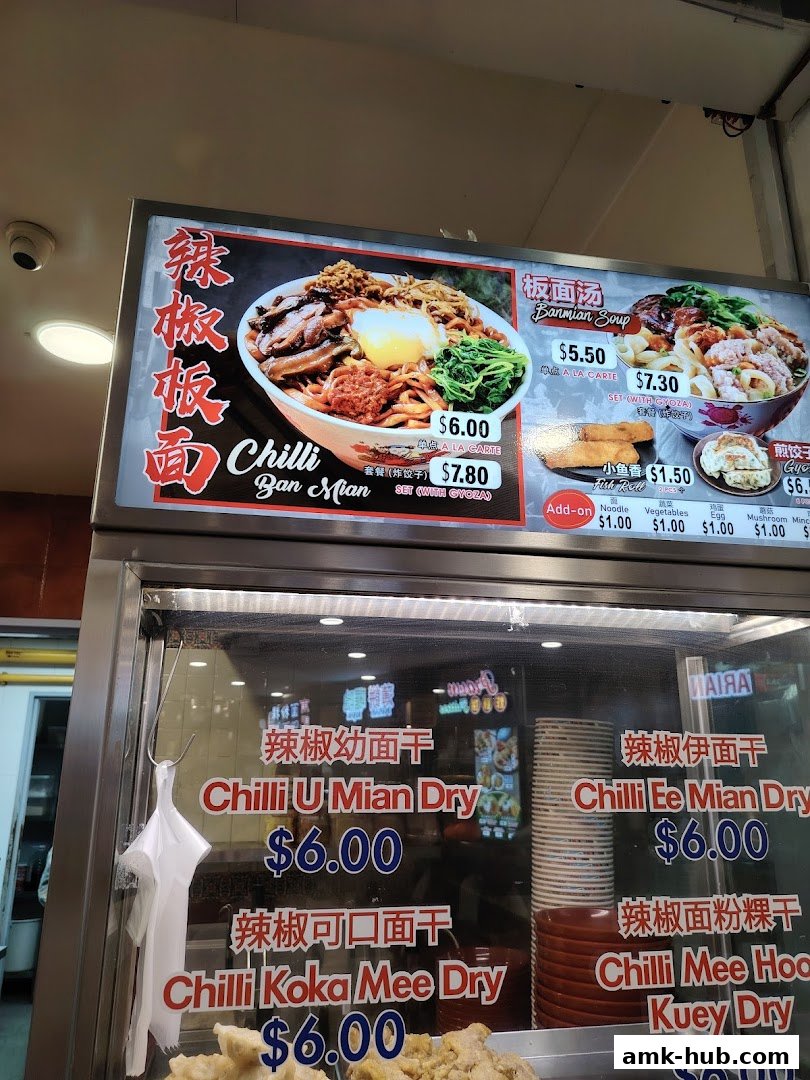 A close-up of a food stall menu displaying various noodle dishes with prices.