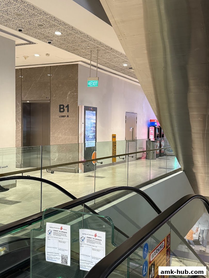 Interior view of a shopping mall with escalators, elevators, and signage.
