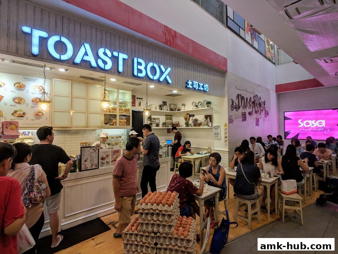 Customers dine at Toast Box AMK Hub, with a view of the counter and food displays.