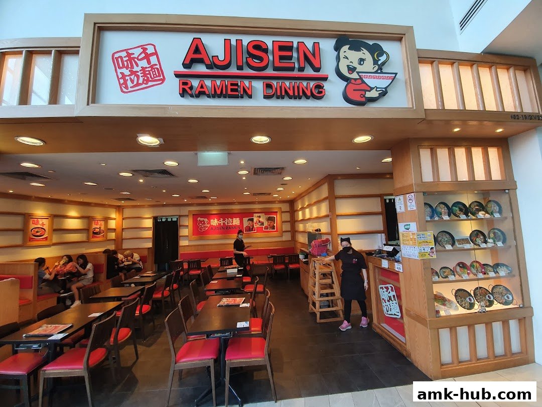 Interior of Ajisen Ramen Dining with tables, chairs, and a display of ramen dishes.