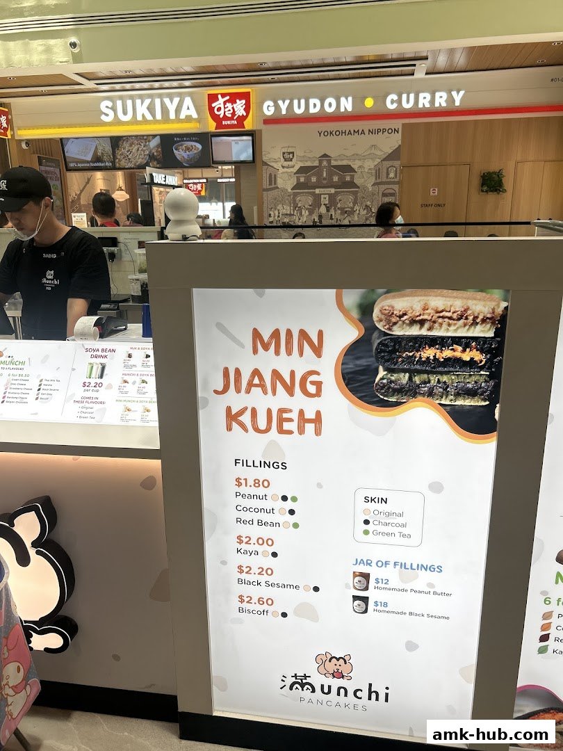 A display board for Munchi Pancakes showcasing Min Jiang Kueh with various fillings and skin options.