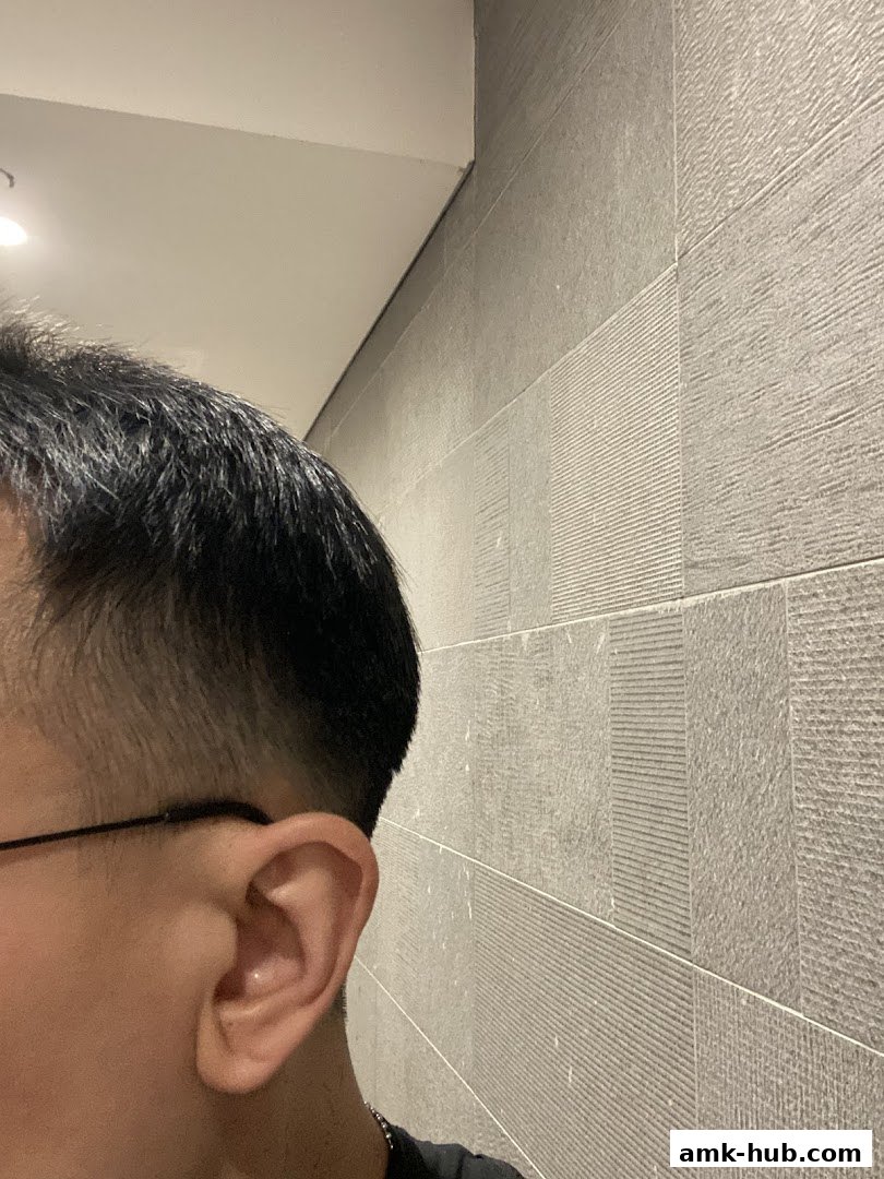Close-up of a person's ear and haircut against a tiled wall.