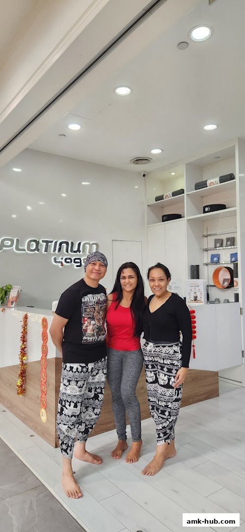 Three people smiling in front of the Platinum Yoga Ang Mo Kio Hub reception area.