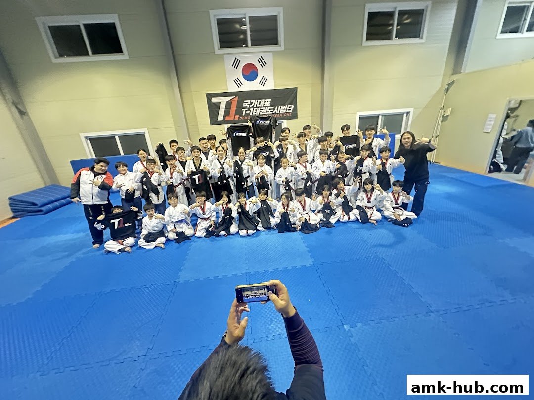 A group of students and instructors pose for a photo at a Taekwondo studio.