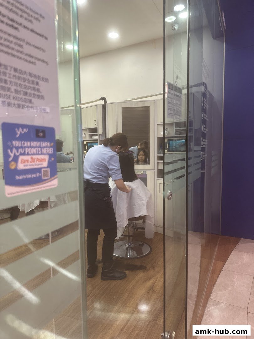 A hairdresser is cutting a customer's hair inside a salon.
