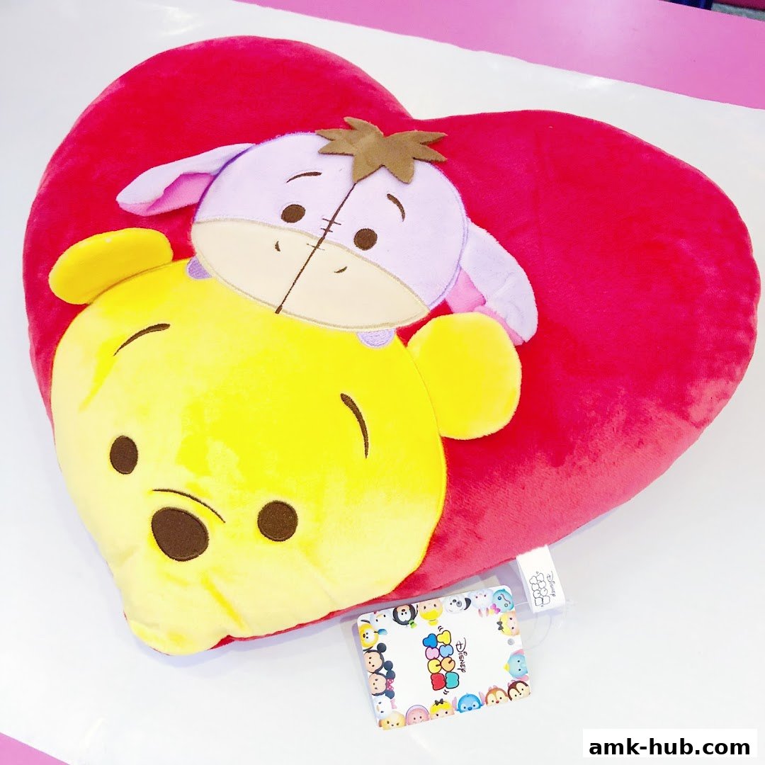 A plush heart-shaped pillow featuring Winnie the Pooh and Eeyore characters.