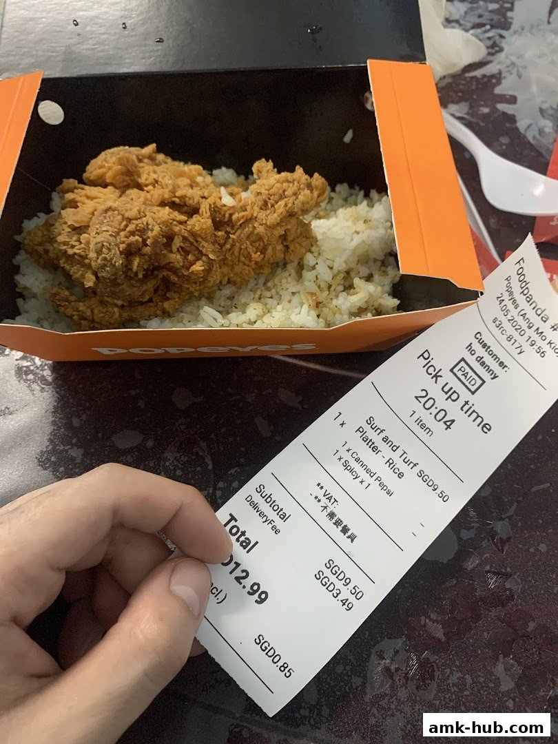 A box of Popeyes fried chicken and rice with a receipt.