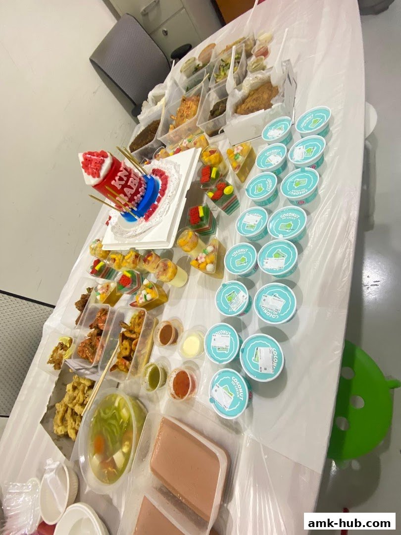 A table laden with various food items, including a cake, desserts, and packaged meals.
