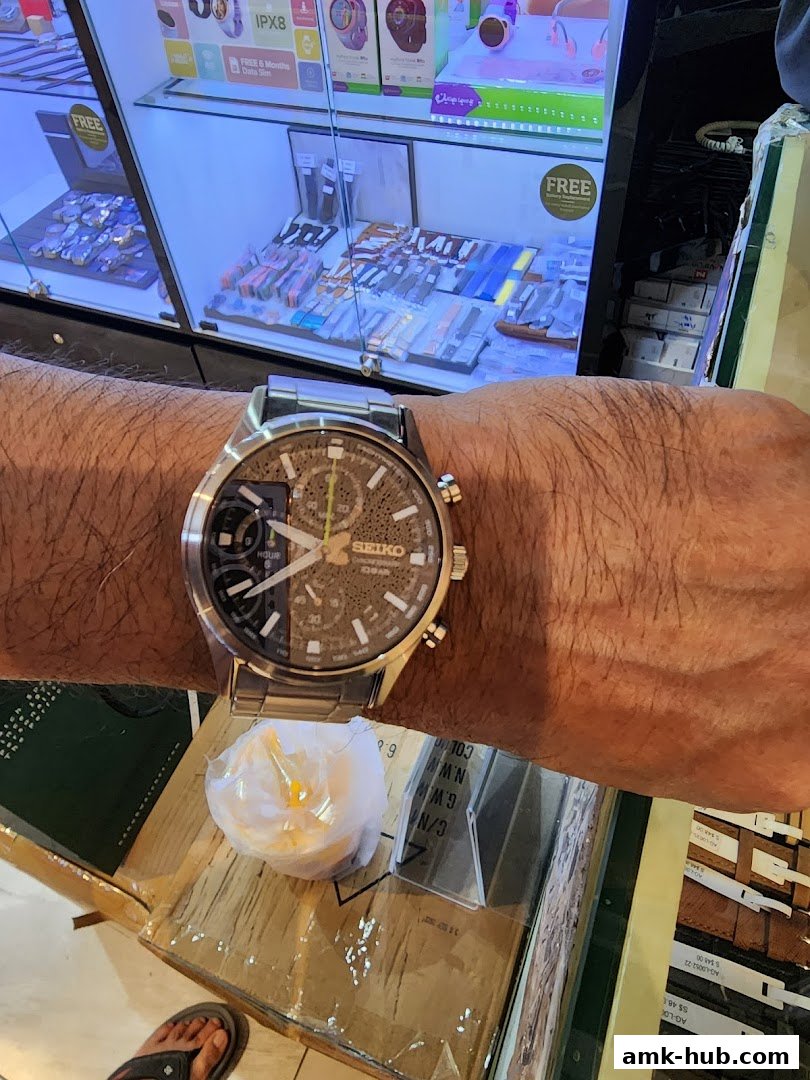 A person wearing a Seiko watch in front of a display of watches and accessories.