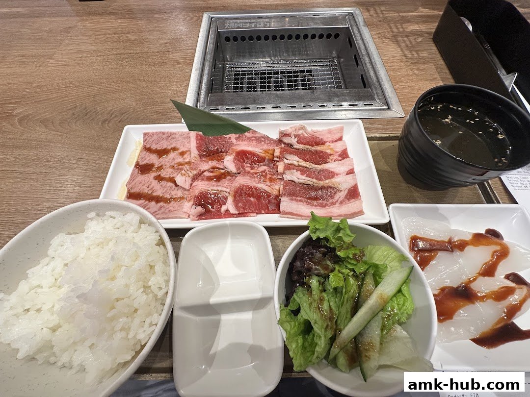 A table setting at Yakiniku Like AMK Hub with grilled meat, rice, salad, and soup.