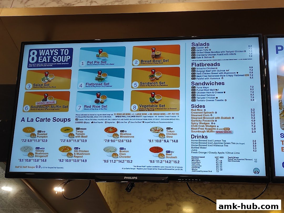 A digital menu board displaying various soup sets, a la carte soups, salads, flatbreads, sandwiches, sides, and drinks.