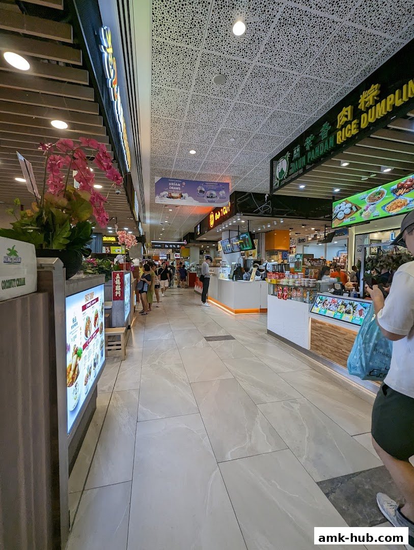 A busy food court with various stalls, including 'Each A Cup', showcasing diverse food options.