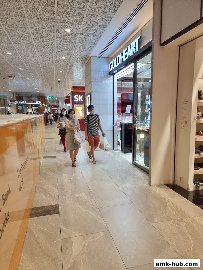 People walking past the Goldheart Jewelry store entrance in a mall.