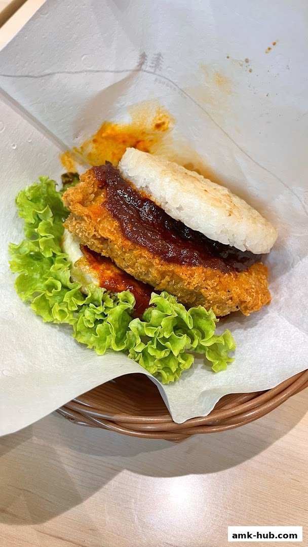 A close-up of a MOS Burger rice burger with lettuce and sauce, served in a basket.