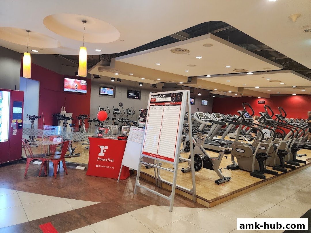 Interior view of a Fitness First gym with treadmills, stationary bikes, and a leaderboard.