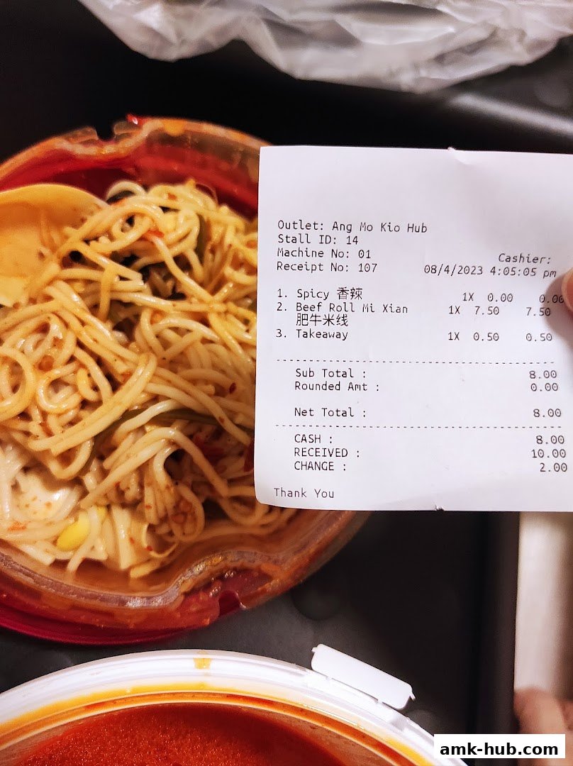 A close-up of a bowl of noodles with a receipt showing food items and prices.