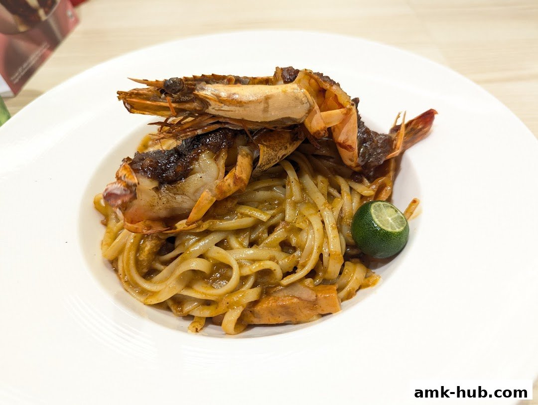 A plate of noodles topped with grilled prawns and a lime wedge.