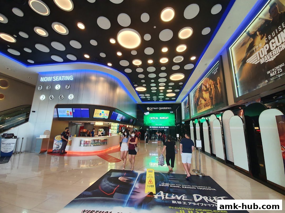 Interior of a modern cinema lobby with movie posters, a concession stand, and seating information.