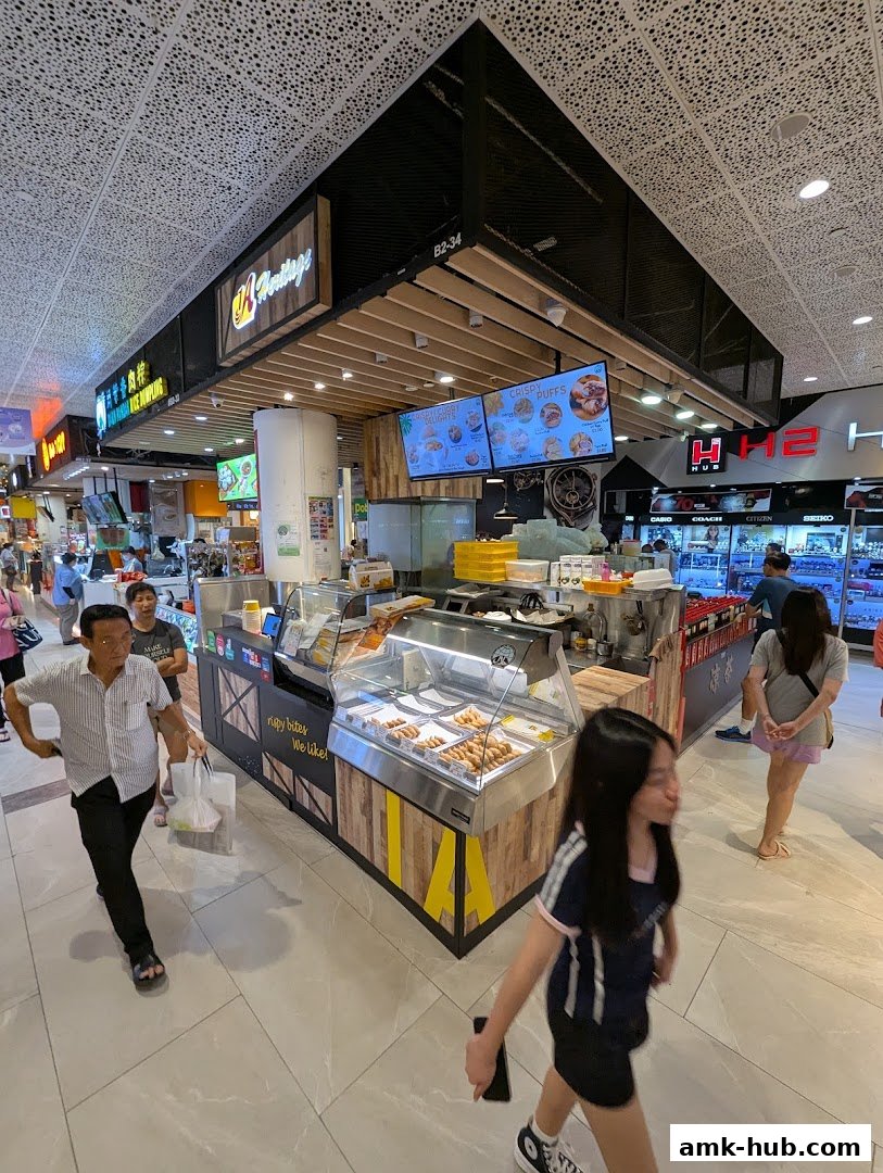 A food stall named 1A Heritage with display cases of food and digital menus above.