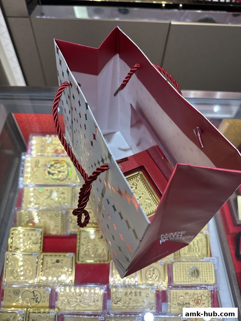 A shopping bag with a star pattern is held over a display of gold bars at SK Jewellery.