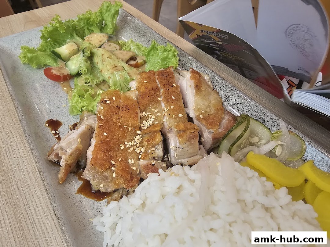 A plate of crispy chicken with rice, salad, and pickles, garnished with sesame seeds.